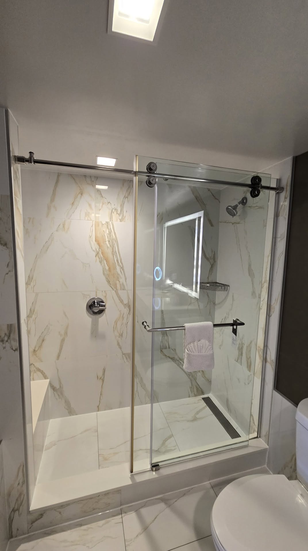 Standard King room bathroom with sliding glass barn-door walk-in shower and bench