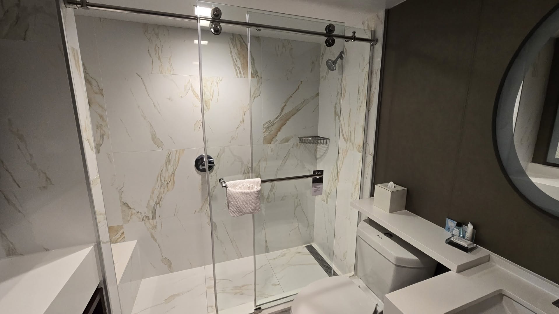 Calacatta marble walk-in shower with sliding glass barn door and bench