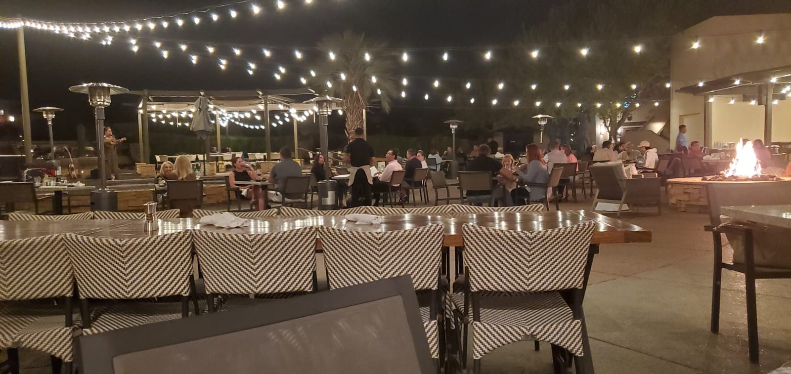 Guests gathered around glowing fire pits enjoying live acoustic music on Rita's terrace. Live acoustic music and fire pit ambiance on Rita's patio