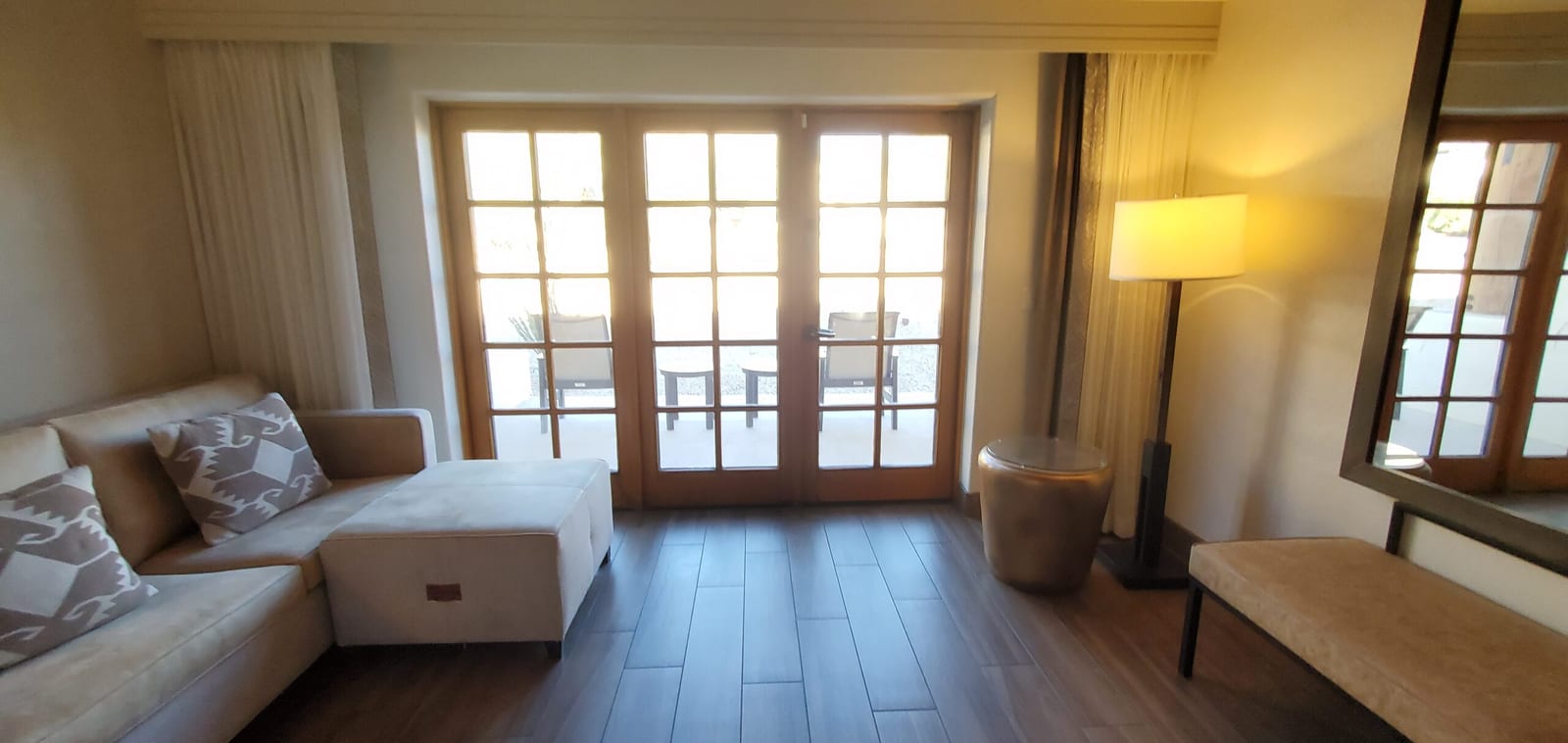 Comfortable chaise lounge and decorative accent pillows flanking French doors to the patio. Sectional chaise lounge situated beside French terrace doors