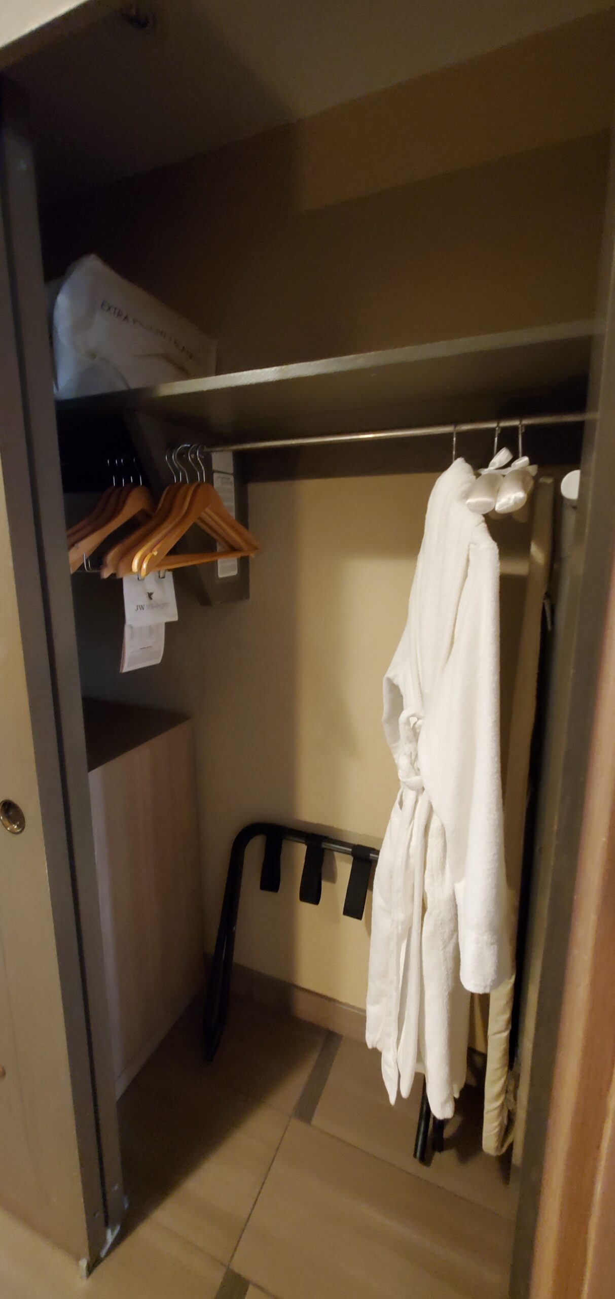 Spacious walk-in closet outfitted with JW Marriott waffle bathrobes and cedar luggage shelving. Walk-in dressing closet with waffle bathrobe and luggage storage