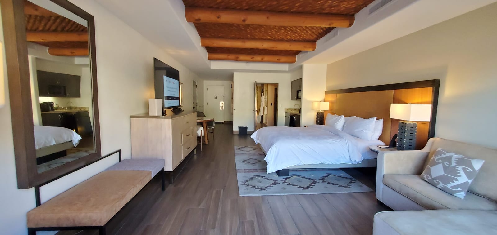 Wide interior view of Casita #287 showing king bed, sleeper sofa, dressing mirror, and media console. Panoramic interior overview looking back from the patio toward the foyer