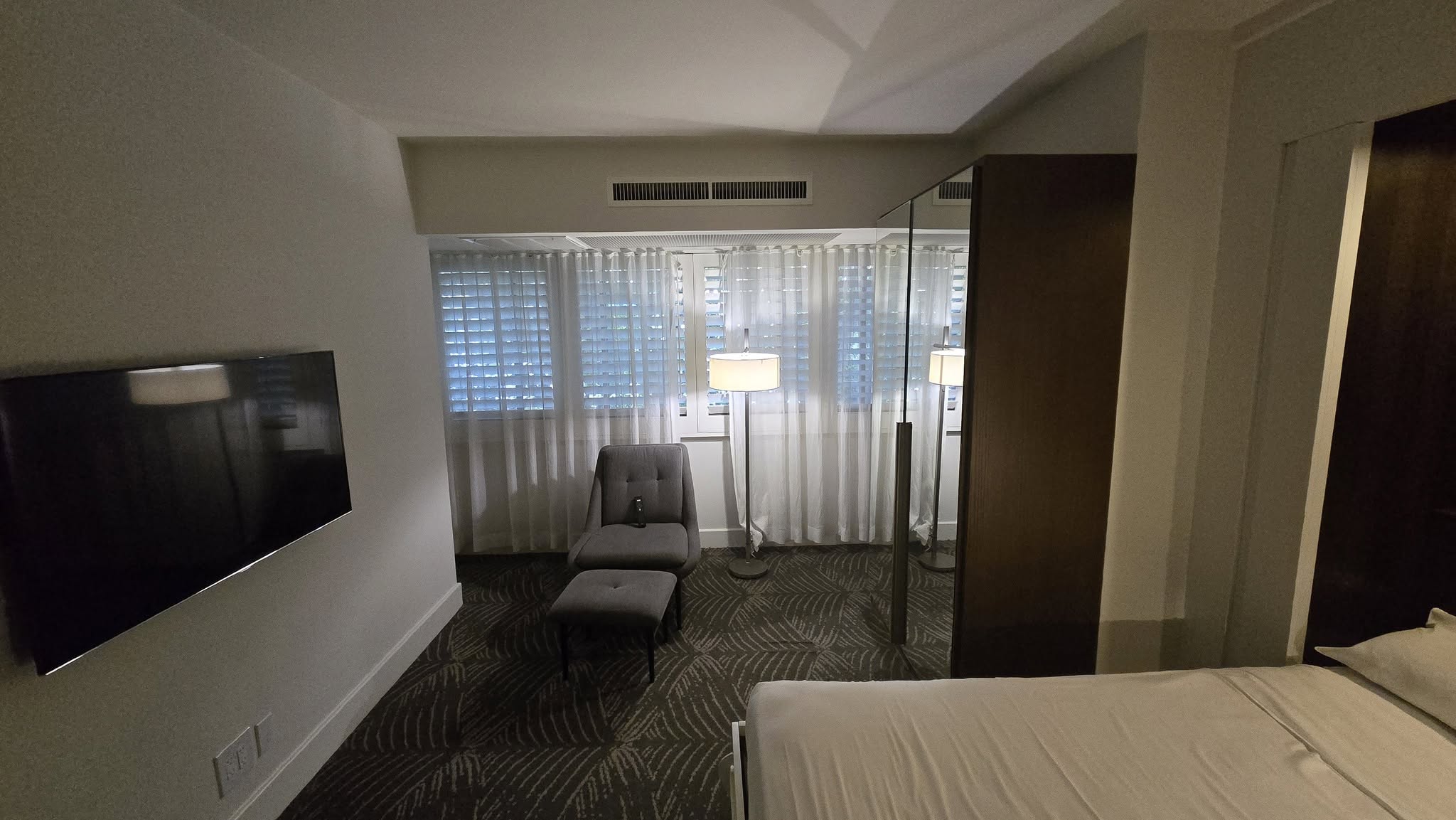 Master bedroom lounge armchair, ottoman, smart TV, and plantation shutters
